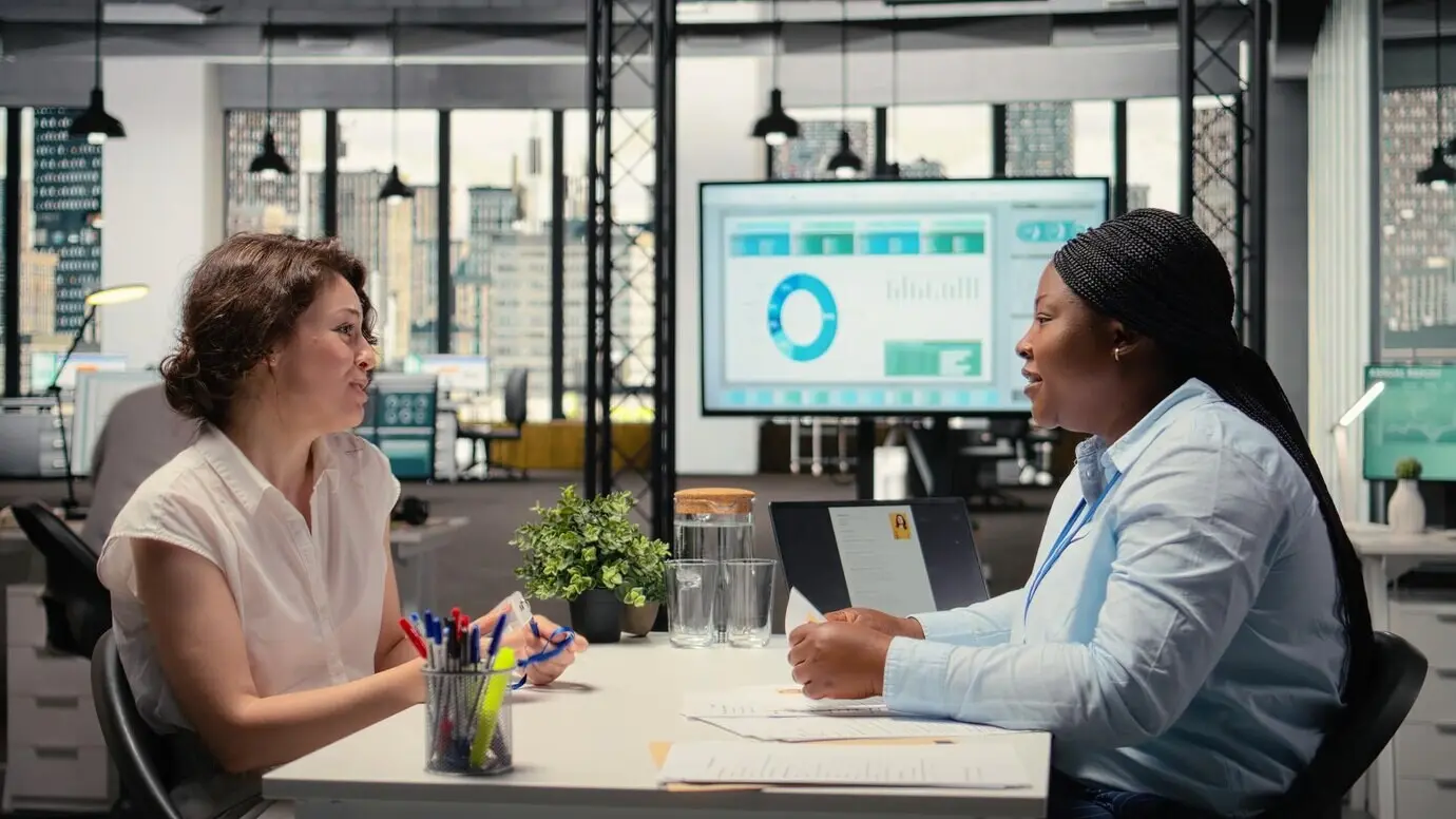 Новый сотрудник обменивается рукопожатием и получает идентификационный пропуск безопасности от менеджера по персоналу на встрече по онбордингу.